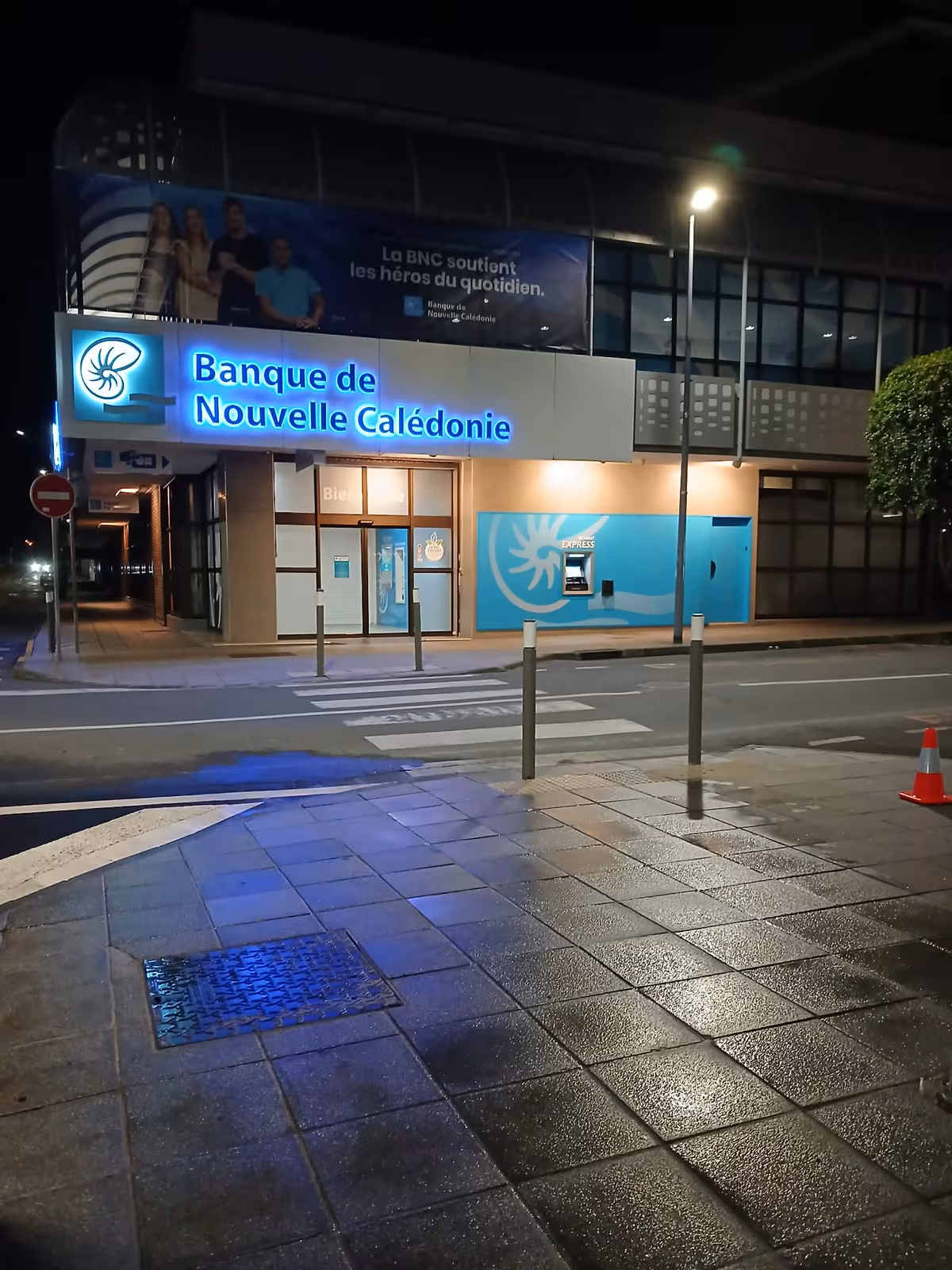 Agent ABC Support en gilet haute visibilité nettoyant de nuit les trottoirs d'un établissement bancaire à Nouméa